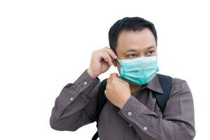Adult Asian business man is wearing medical face mask before leaving home to go to the office while isolated on white background. photo