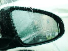 Close up image of a car mirror through the wet window. photo