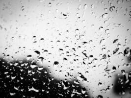 Black and white image of a wet glass. Stormy sky behind the wet glass. photo