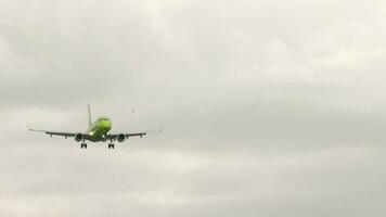 Jet aircraft approaching landing, front view. Passenger plane flies in cloudy gray sky. Tourism and travel concept video