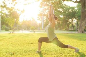 Female jogger. Fit young Asian woman with green sportswear stretching muscle in park before running and enjoying a healthy outdoor. Fitness runner girl in public park. Wellness being concept photo