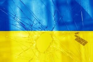 Bullet hole, cracks in the glass on a yellow-blue background. Ukraine flag on broken glass texture. Concept, Russian-Ukrainian war photo