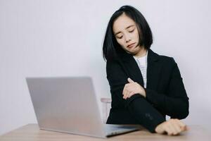 concepto oficina síndrome, joven asiático hembra oficina trabajador es cansado desde difícil trabajar, hombro dolor debido a trabajando horas consecutivamente foto