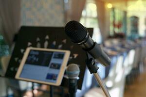 A wireless microphone on a stand against the blurred background of a tablet screen for singers to sing to entertain customers in a restaurant. Soft and selective focus. photo