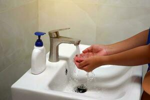 asiático mujer torneado en el grifo a el lavabo a limpiar purificar suciedad y gérmenes después yendo a el baño o recoger arriba alimento. suave y selectivo enfocar. foto