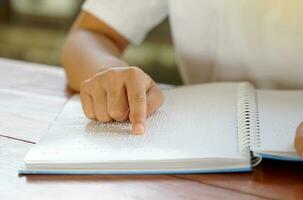 visualmente dañado persona lee con su dedos un libro escrito en braille eso es escrito para esos quien son visualmente dañado o ciego. eso es un especial código generado desde 6 6 puntos en el caja. foto