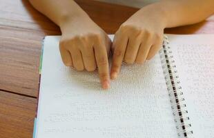 visualmente dañado persona lee con su dedos un libro escrito en braille eso es escrito para esos quien son visualmente dañado o ciego. eso es un especial código generado desde 6 6 puntos en el caja. foto