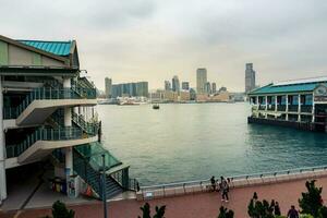 Hong Kong,March 25,2019-View of the Hong Kong skyscrapers from the Star ferry pier near the ferris wheel on the Victoria Harbour during a cloudy day photo