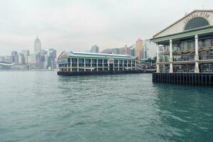 Hong Kong,March 25,2019-View of the Hong Kong skyscrapers from the Star ferry pier near the ferris wheel on the Victoria Harbour during a cloudy day photo