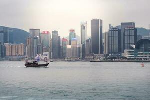 Hong Kong,March 25,2019-View of the Hong Kong skyscrapers and traditional boat from the Avenue of star on  the Victoria Harbour during a cloudy day photo