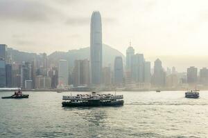 Hong Kong,March 25,2019-View of the Hong Kong skyscrapers and traditional boat from the Avenue of star on  the Victoria Harbour during a cloudy day photo