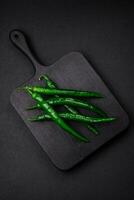 Fresh hot green chili peppers on a dark concrete background photo