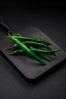 Fresh hot green chili peppers on a dark concrete background photo