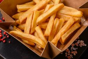 delicioso crujiente francés papas fritas con sal y especias en un cartulina caja foto