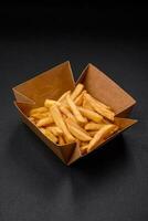 Delicious crispy french fries with salt and spices in a cardboard box photo