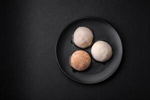 Delicious sweet mochi dessert with toppings on a dark concrete background photo