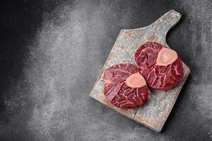 Fresh raw beef steak with bone or ossobuco with salt, spices and herbs photo