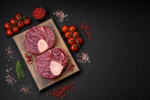 Fresh raw beef steak with bone or ossobuco with salt, spices and herbs photo