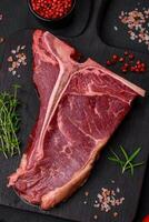 Raw juicy beef t-bone steak with salt, spices and herbs photo