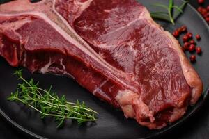 Raw juicy beef t-bone steak with salt, spices and herbs photo