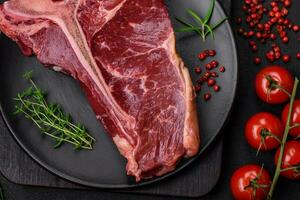 Raw juicy beef t-bone steak with salt, spices and herbs photo