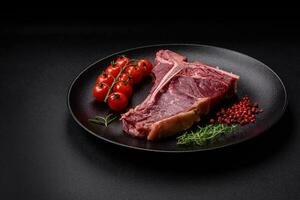 Raw juicy beef t-bone steak with salt, spices and herbs photo