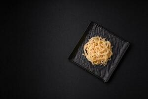 Delicious dried squid in the form of shavings with salt and spices on a ceramic plate photo