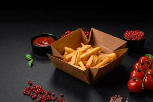 Delicious crispy french fries with salt and spices in a cardboard box photo