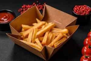 Delicious crispy french fries with salt and spices in a cardboard box photo