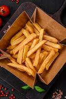 Delicious crispy french fries with salt and spices in a cardboard box photo