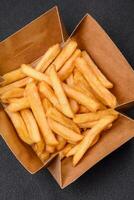 Delicious crispy french fries with salt and spices in a cardboard box photo