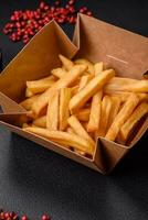 Delicious crispy french fries with salt and spices in a cardboard box photo