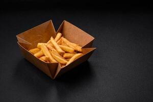 Delicious crispy french fries with salt and spices in a cardboard box photo