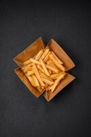 Delicious crispy french fries with salt and spices in a cardboard box photo