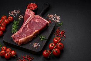 Raw juicy beef t-bone steak with salt, spices and herbs photo