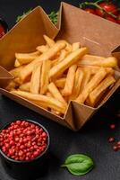 Delicious crispy french fries with salt and spices in a cardboard box photo