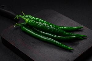 Fresh hot green chili peppers on a dark concrete background photo