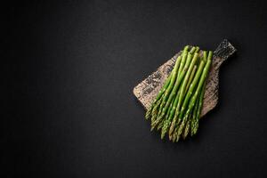 Delicious fresh sprigs of asparagus on a dark textured background photo