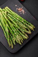 Delicious fresh sprigs of asparagus on a dark textured background photo