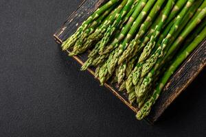 Delicious fresh sprigs of asparagus on a dark textured background photo