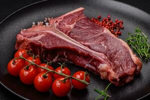 Raw juicy beef t-bone steak with salt, spices and herbs photo