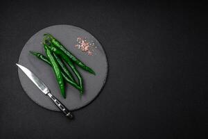 Fresh hot green chili peppers on a dark concrete background photo