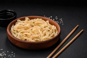 Delicious dried squid in the form of shavings with salt and spices on a ceramic plate photo