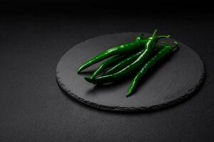 Fresh hot green chili peppers on a dark concrete background photo
