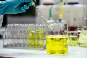 Scientist uses a dropper to aspirate sample solution mixed with an emulsifier and active compound in a beaker for formulation test of the cosmetic product. Research and Development cosmetics. photo