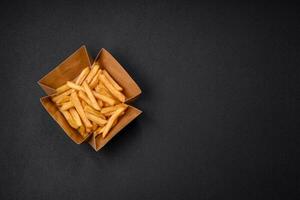 Delicious crispy french fries with salt and spices in a cardboard box photo