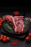 Raw juicy beef t-bone steak with salt, spices and herbs photo