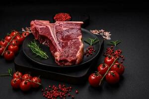 Raw juicy beef t-bone steak with salt, spices and herbs photo