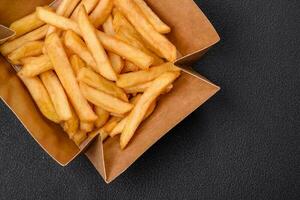 Delicious crispy french fries with salt and spices in a cardboard box photo