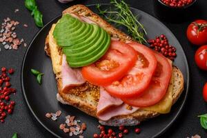 delicioso nutritivo A la parrilla brindis con jamón, queso, Tomates y aguacate foto